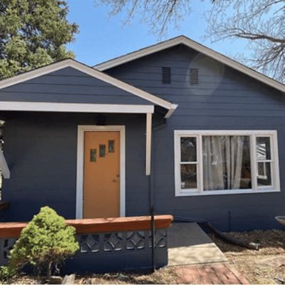 A blue shaded house with a tan colored door with white trim, by kind home solutions.